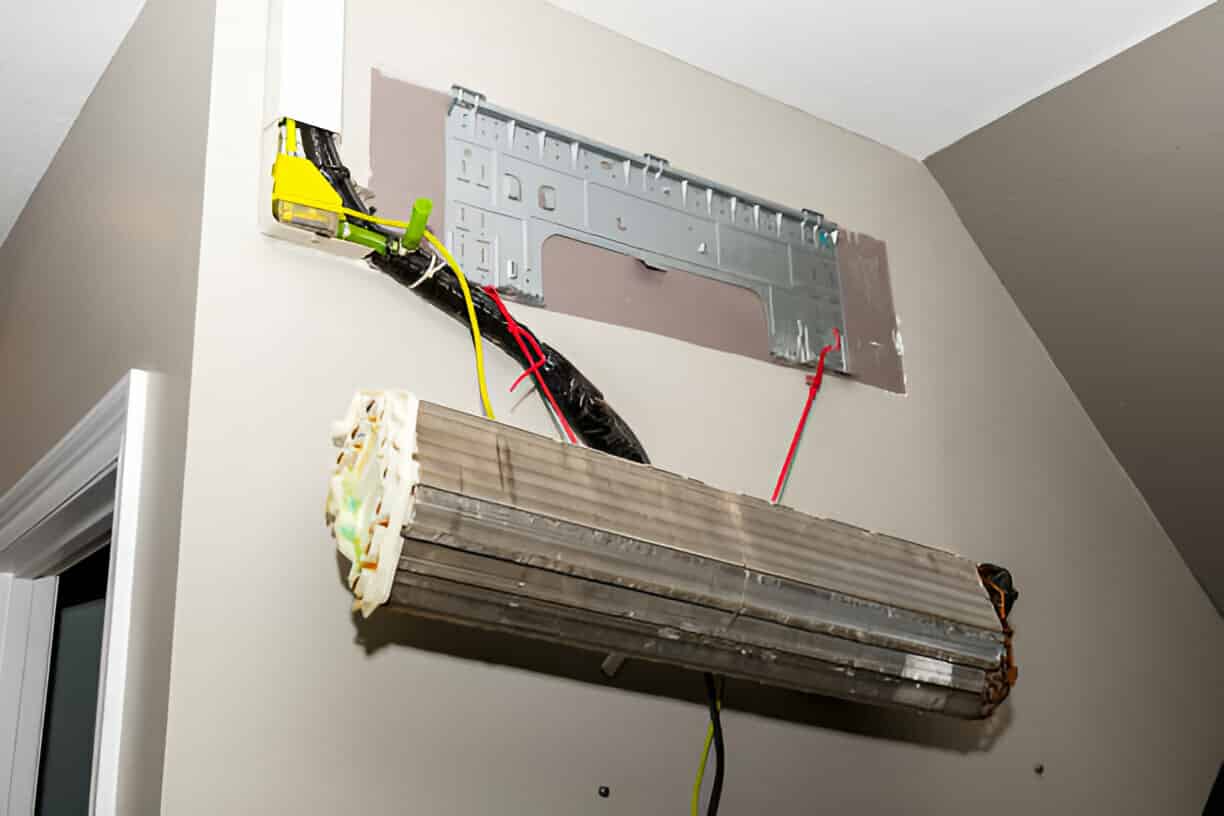 Dismantled air conditioning unit with exposed wiring and mounting plate