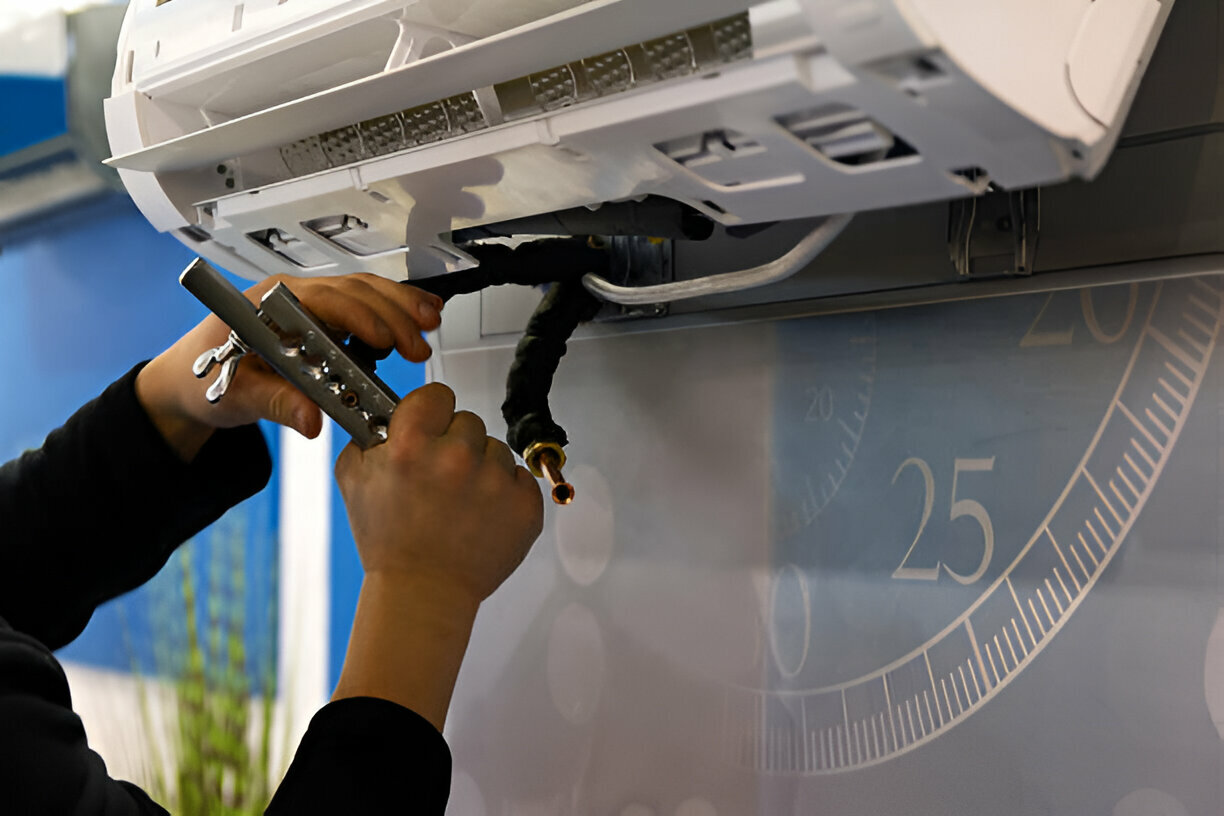 Technician repairing air conditioning unit with wrench near measurement scale