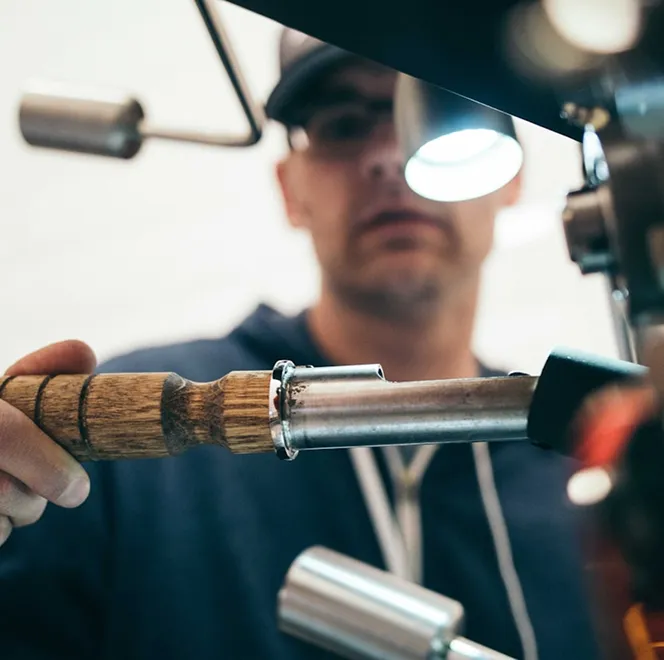 Craftsman working on metal tool under bright workshop lamp