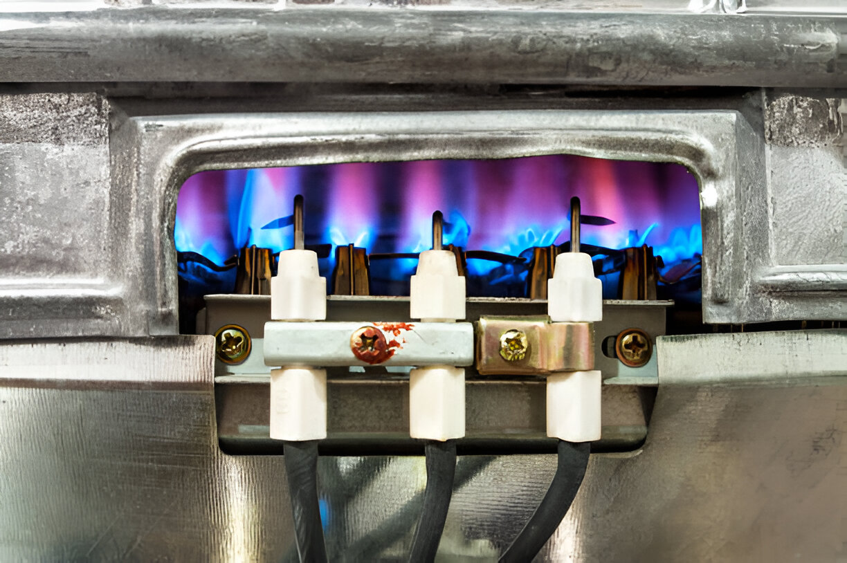 Gas burner with blue and purple flames behind electrical connections