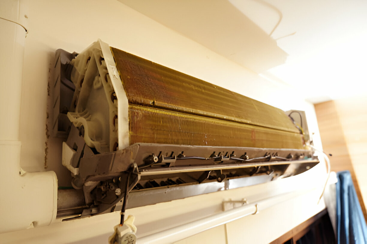 Dusty split-system air conditioner mounted on wall, showing internal components