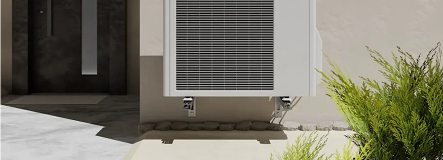 White air conditioner unit mounted on wall with green plants nearby