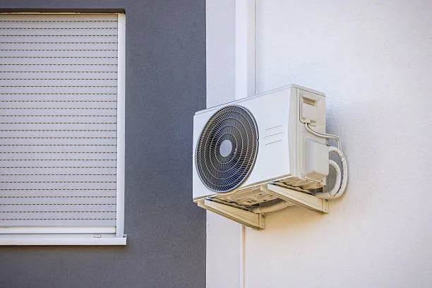 White air conditioning unit mounted on exterior wall next to window