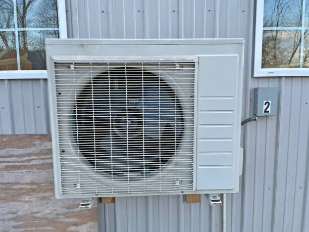 White air source heat pump unit mounted on metal building exterior