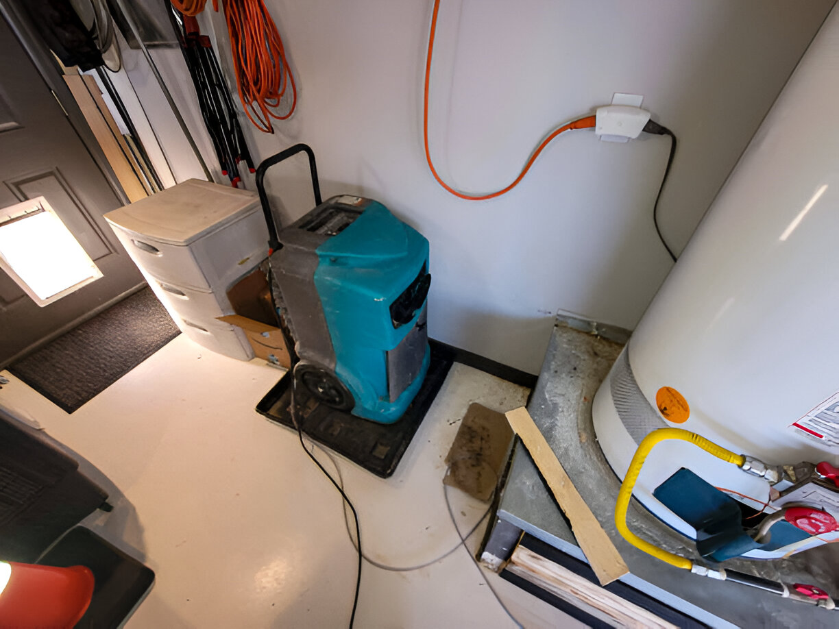 Teal water damage restoration dehumidifier in cluttered utility room