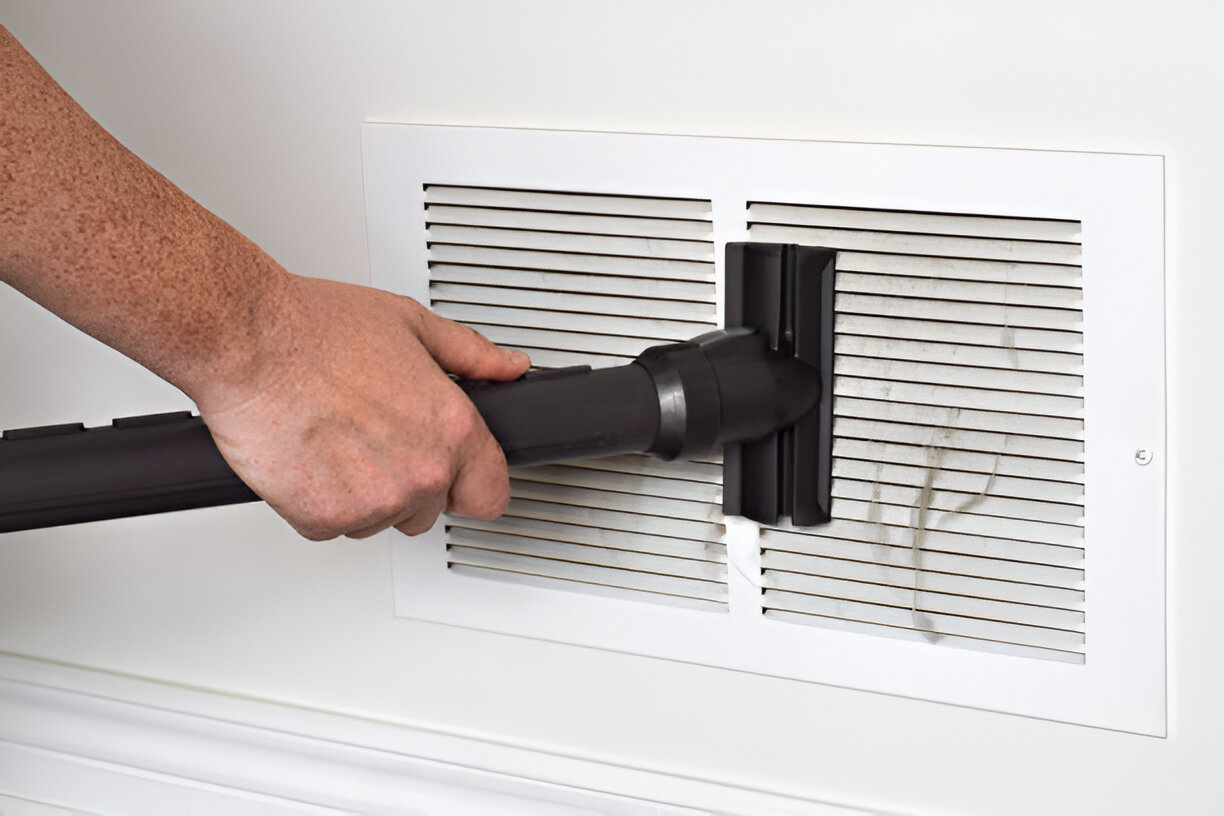 Vacuum cleaner attachment cleaning a white air vent or register