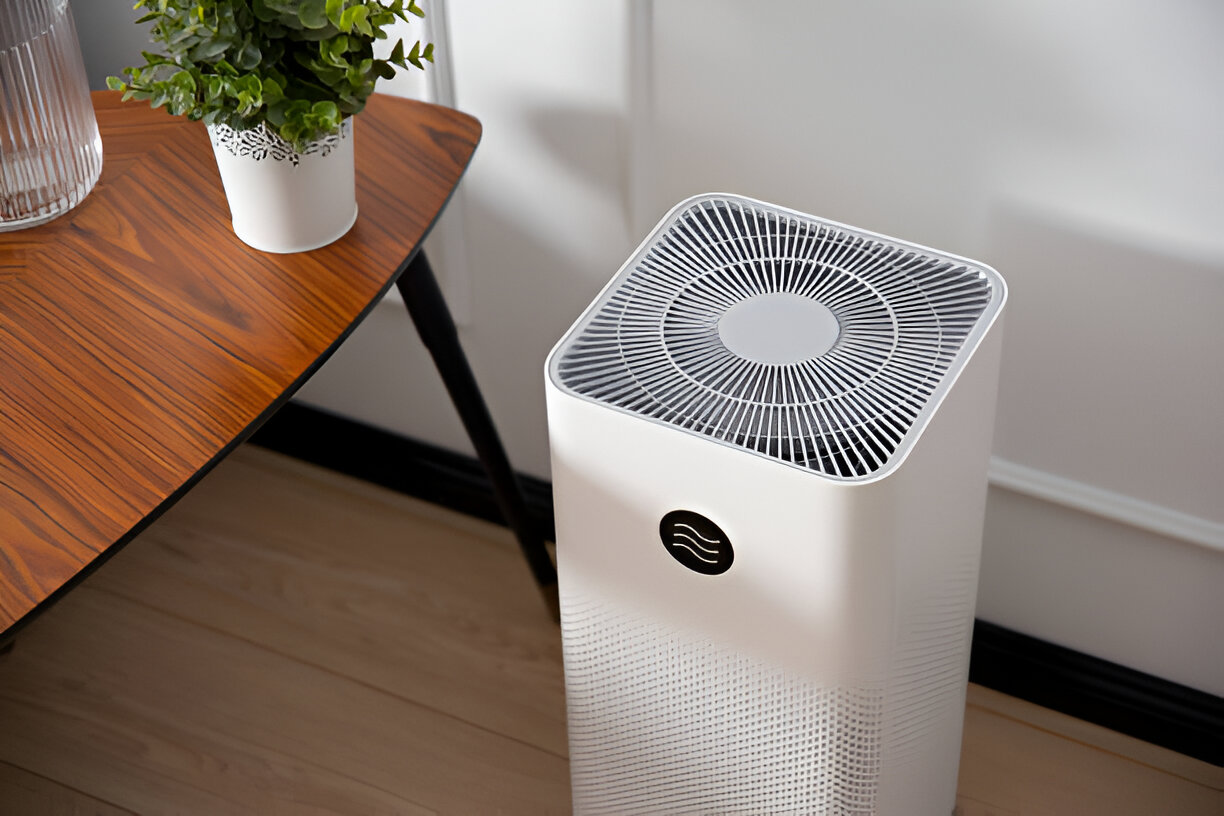 White air purifier on wooden floor next to plant and side table