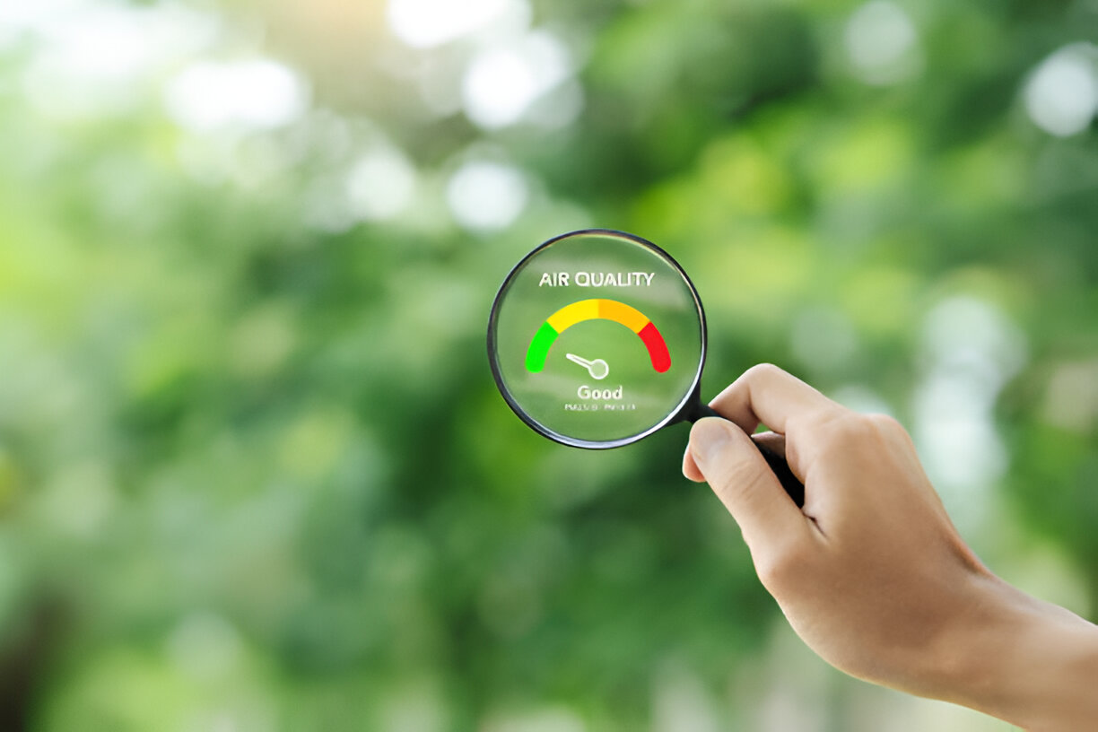 Hand holding magnifying glass showing good air quality meter