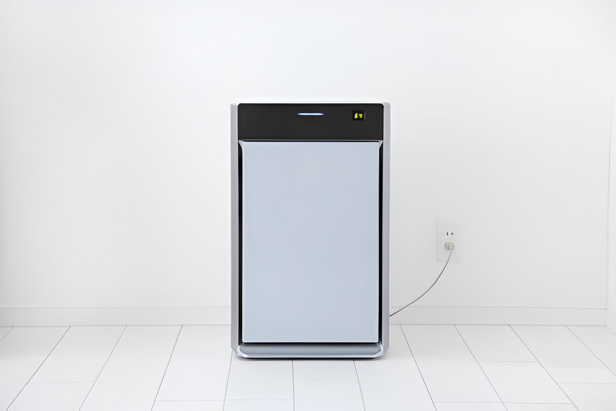 Modern white and silver air purifier on clean floor near electrical outlet