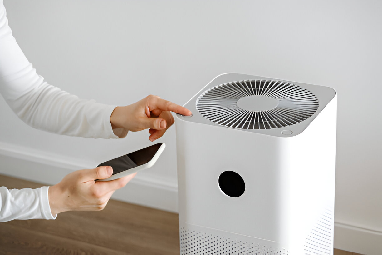 Hand operating a modern white air purifier with digital display