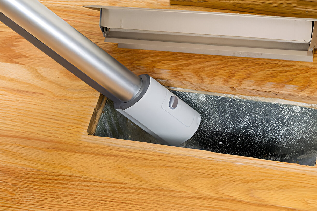 Vacuum cleaner attachment cleaning dust from wooden floor vent