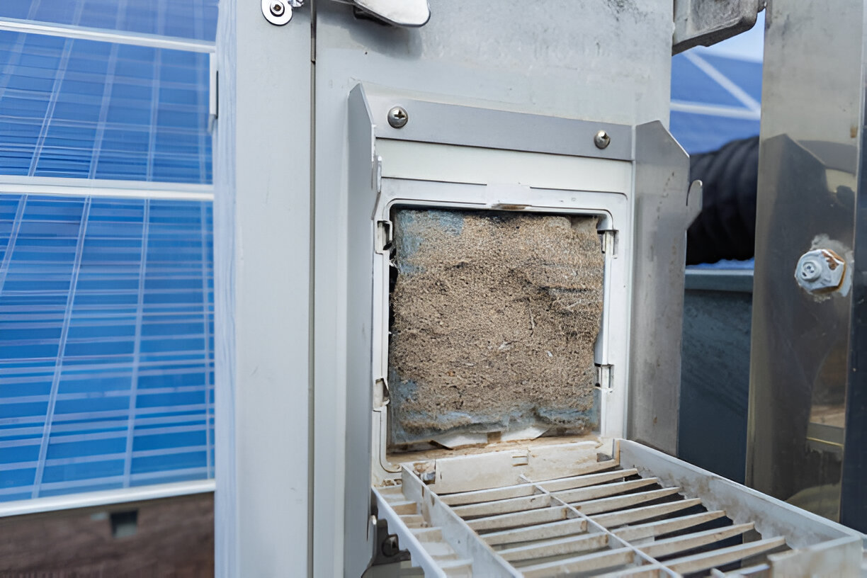 Dusty air filter with solar panel in background, maintenance needed