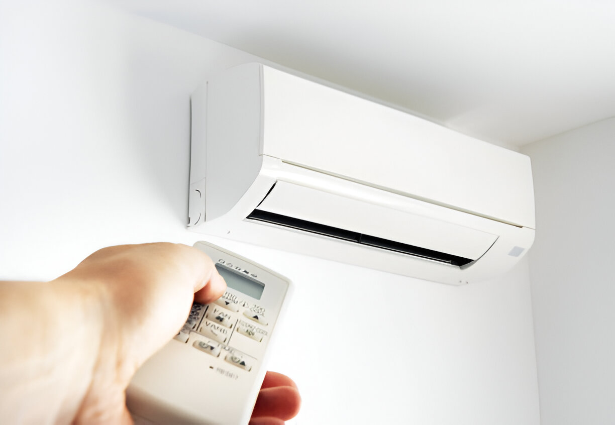 White wall-mounted air conditioner with hand holding remote control