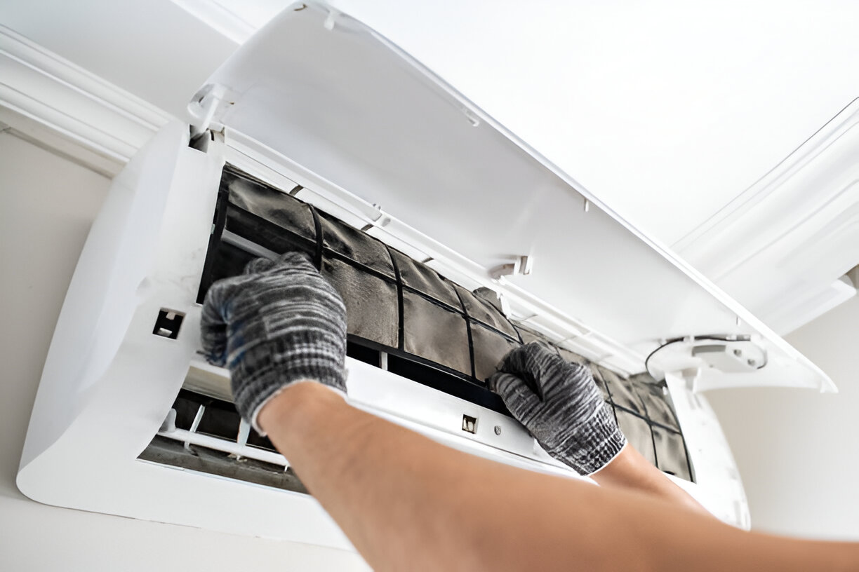 Hands cleaning air conditioner filter with gloved hands