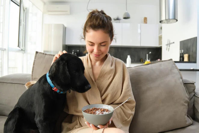 Image of a woman feeding a black dog