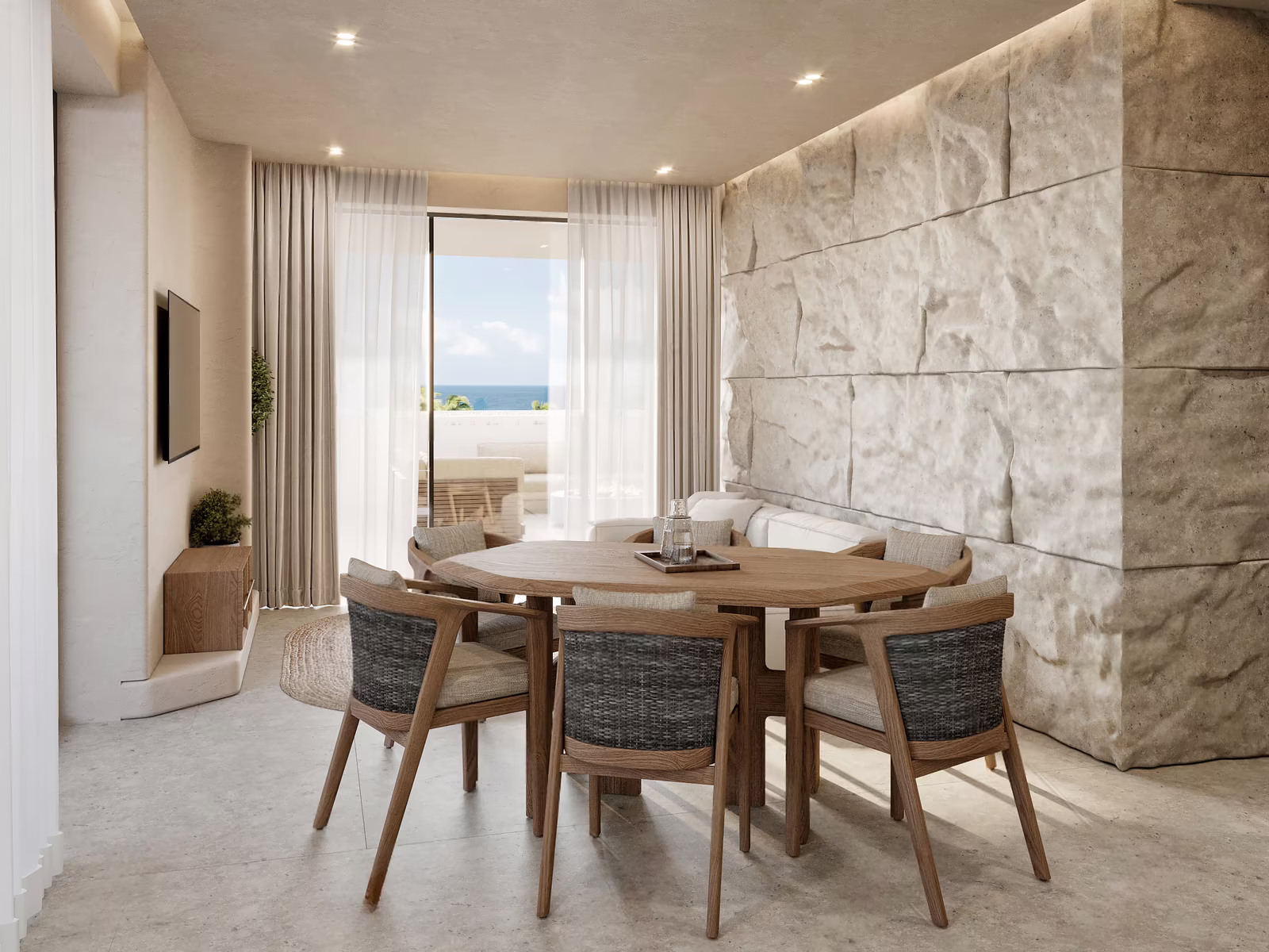 Two bedroom apartment at Azure Paje: round dining table beside a stone wall and sea view