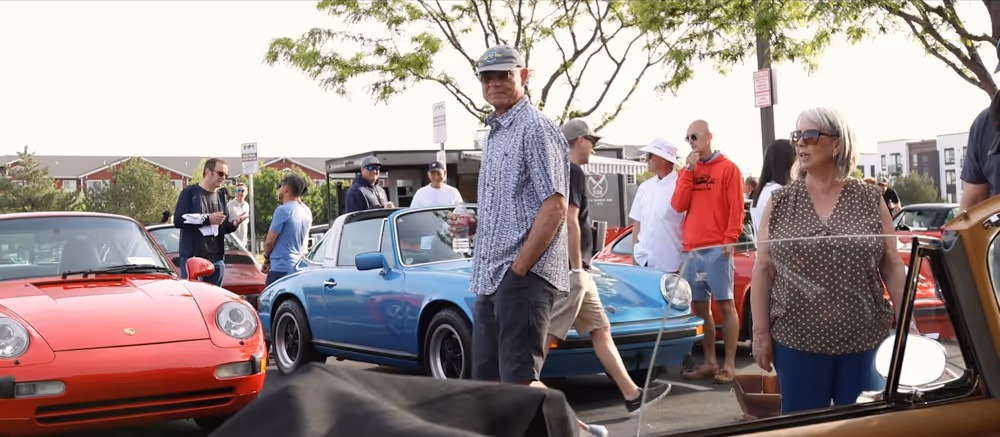 Visitors walking between classic Porsche cars at an Idaho car event.