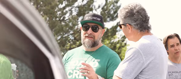 Car enthusiasts discussing a Porsche 911 at Idaho Air