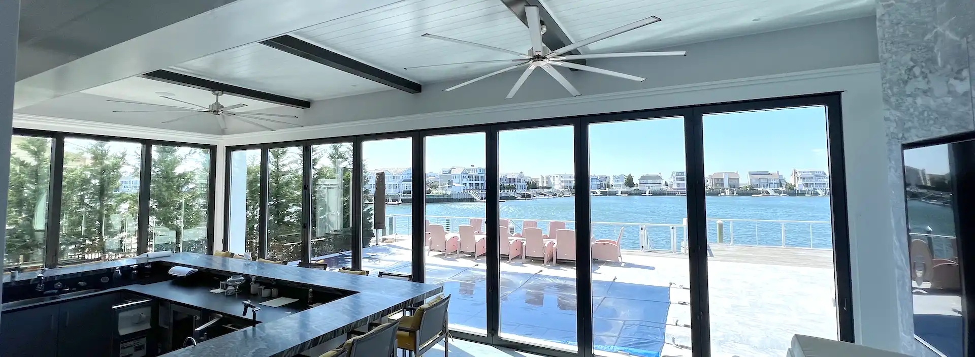 White stucco beachfront home with three large arched Andersen windows and a striped awning above