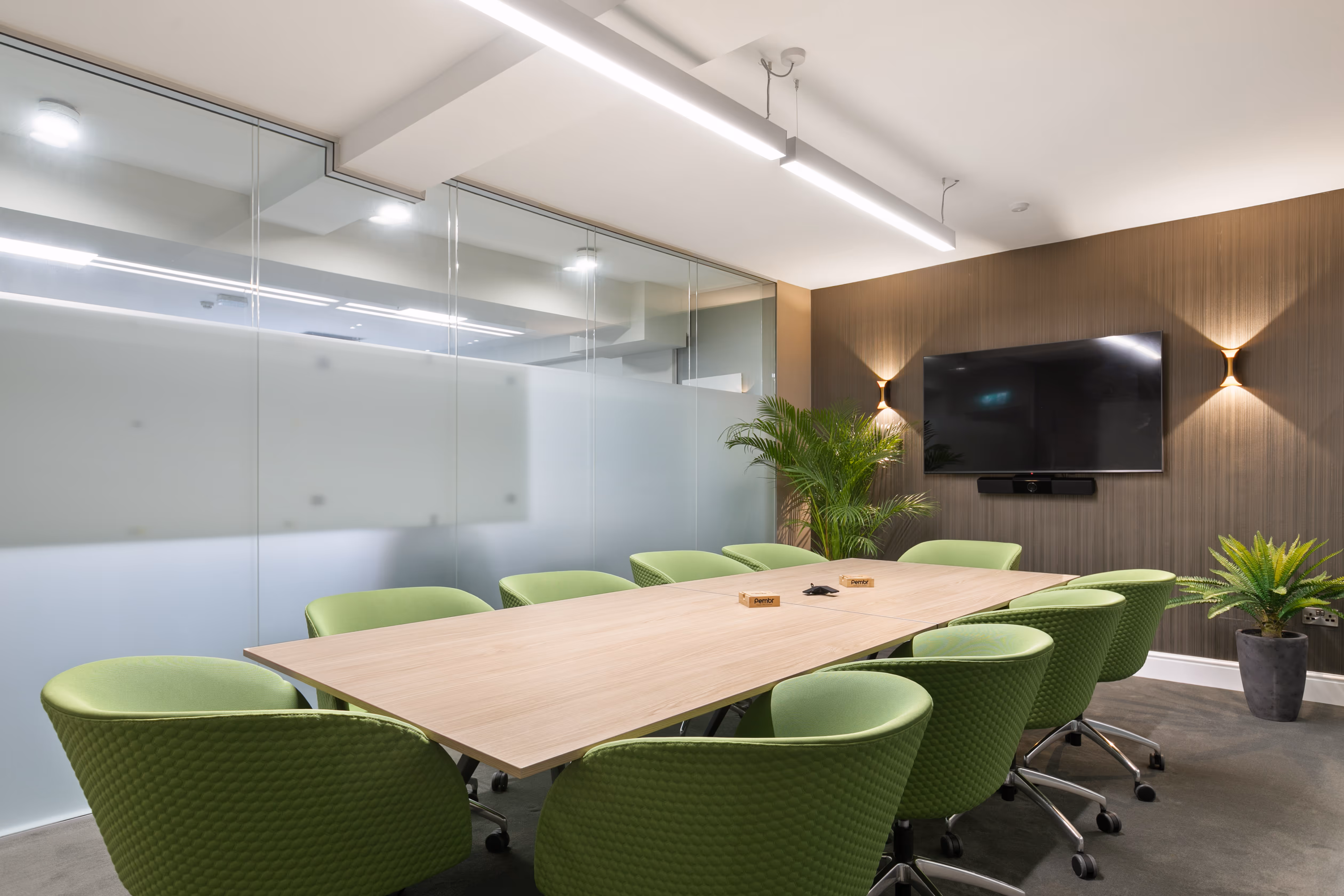 Large boardroom with desk, seats, and tv.