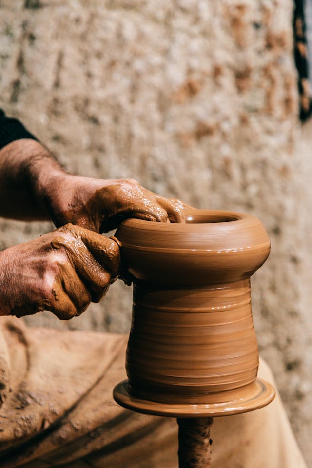 A hand creating a ceramic vase.