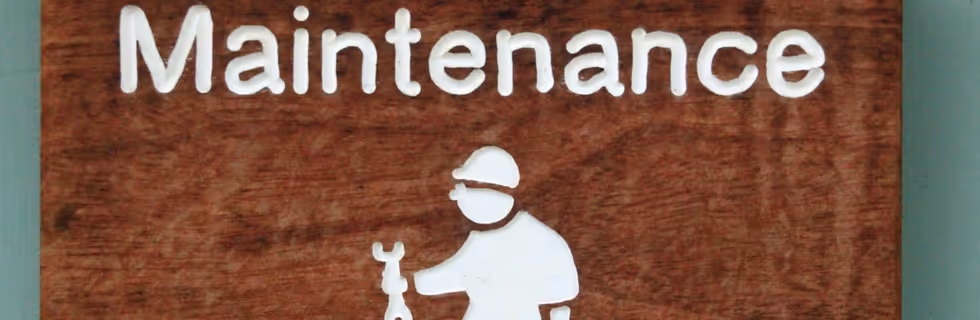 Maintenance sign with worker icon holding wrench on wooden background