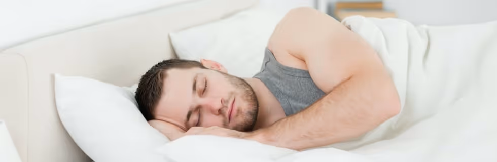 Person sleeping peacefully on white bed with soft pillow
