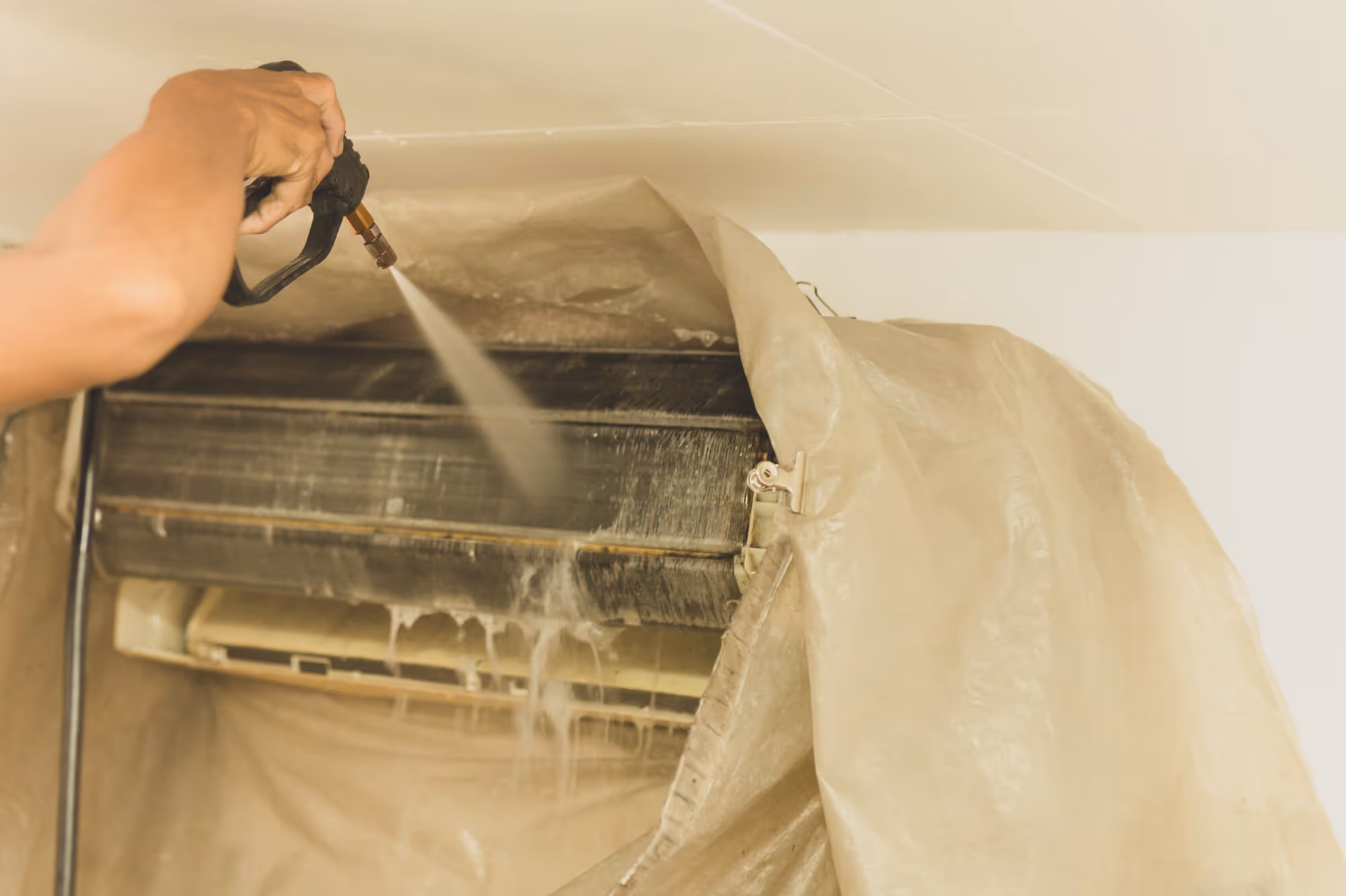 Cleaning air conditioner unit with spray and protective cloth covering