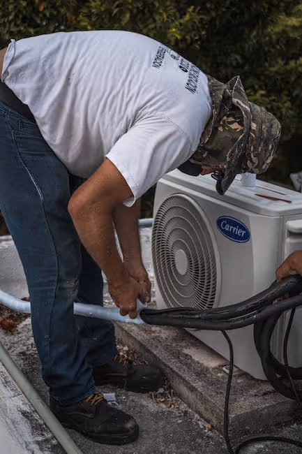 Technician in white shirt installing or repairing an outdoor Carrier air conditioner