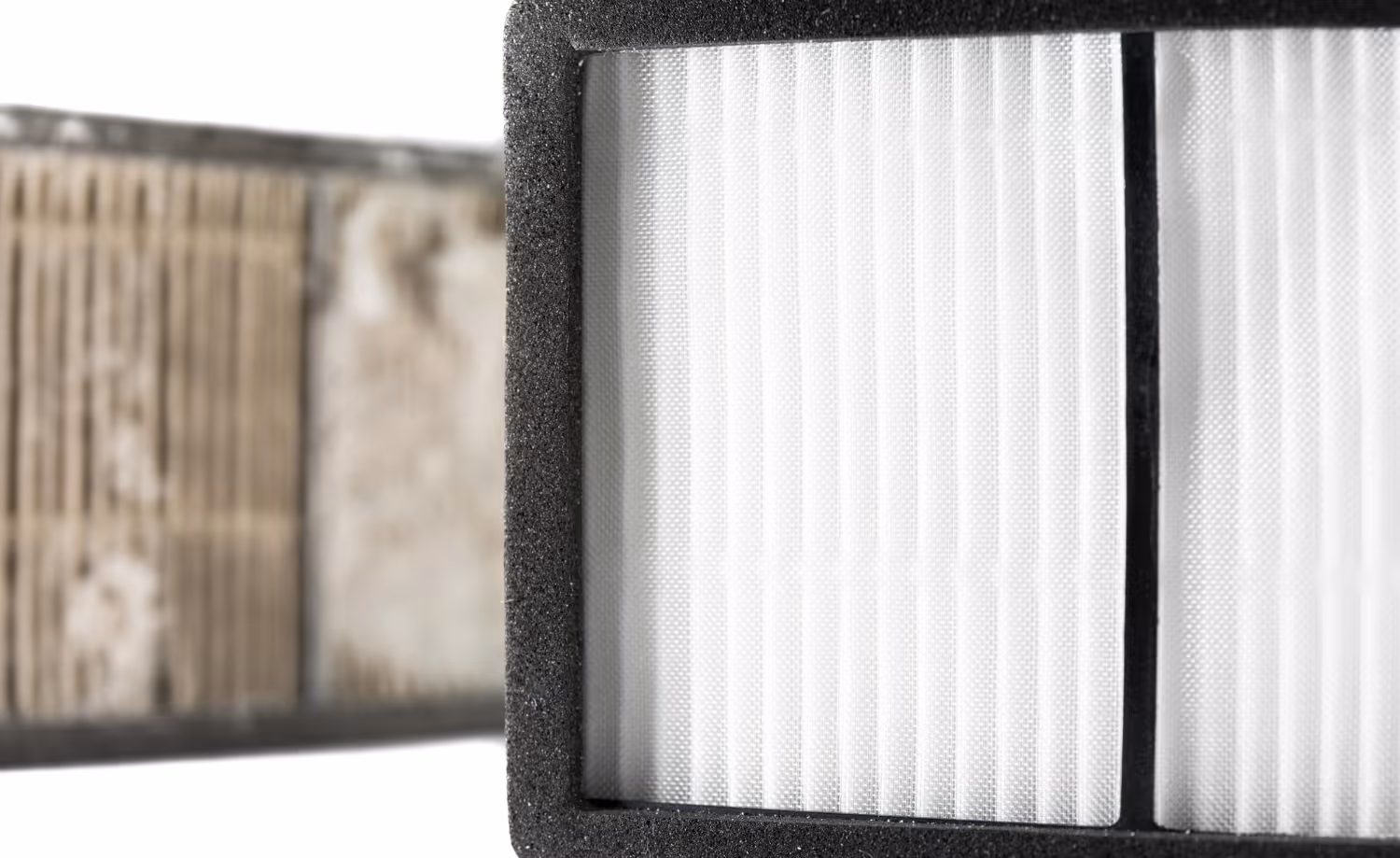 Close-up of a white pleated air filter with black foam edge