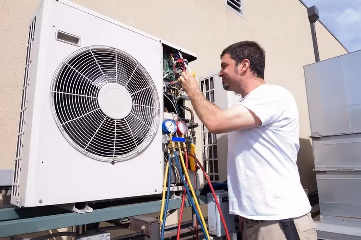 Technician repairing air conditioning unit with diagnostic tools outdoors