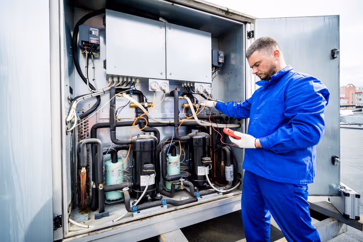 Technician in blue uniform checks industrial cooling system components