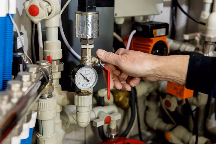 Technician adjusting pressure gauge on complex industrial piping system
