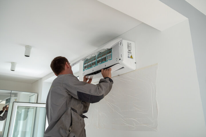 Technician installing wall-mounted air conditioning unit indoors