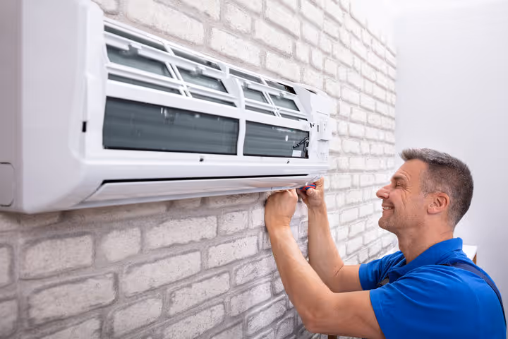 Technician installing or repairing a wall-mounted air conditioning unit