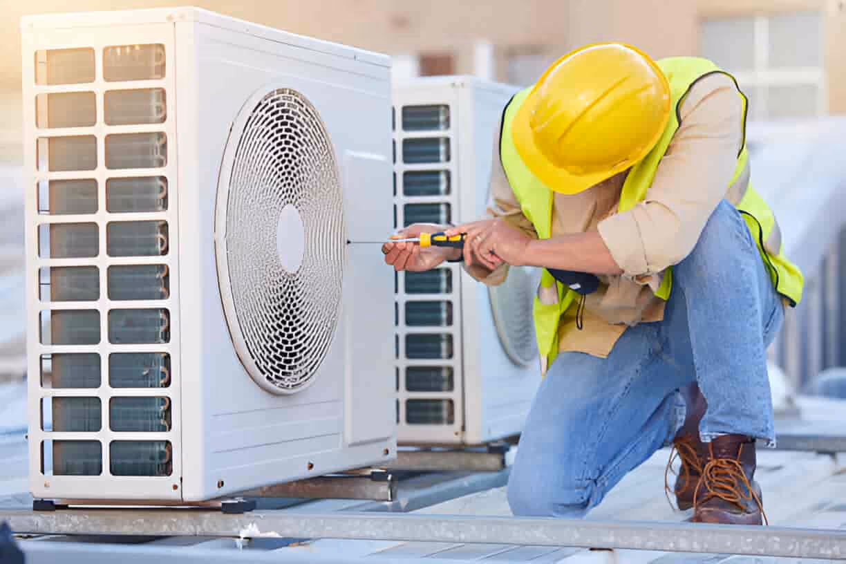 Technician in safety gear repairing an outdoor air conditioning unit