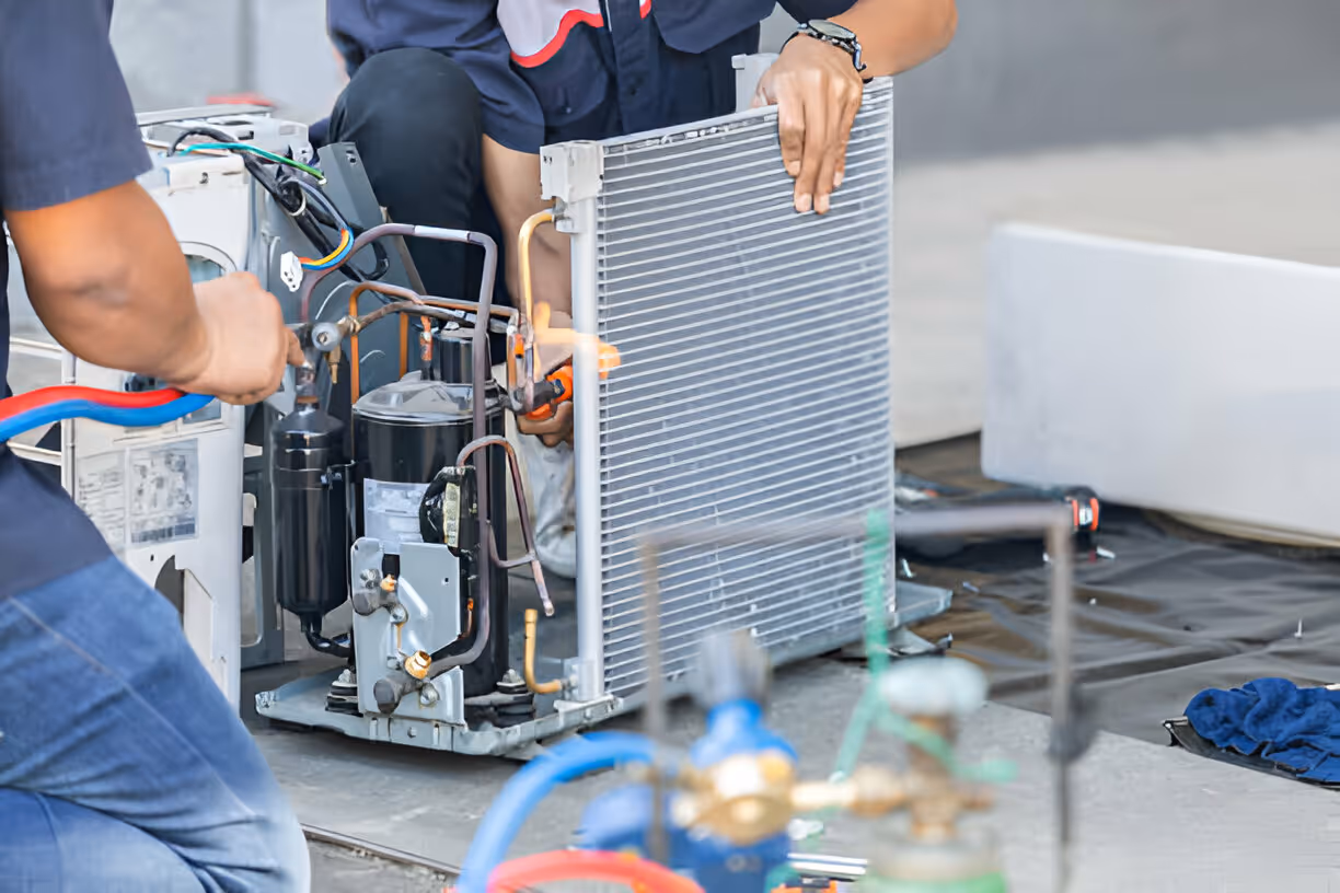 Technician repairing air conditioning unit with condenser and compressor