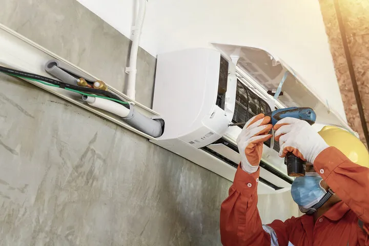 Technician repairing air conditioning unit with tools and protective gear