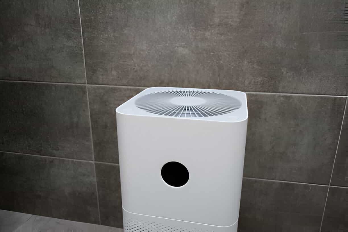 White air purifier with circular fan design against gray tiled wall