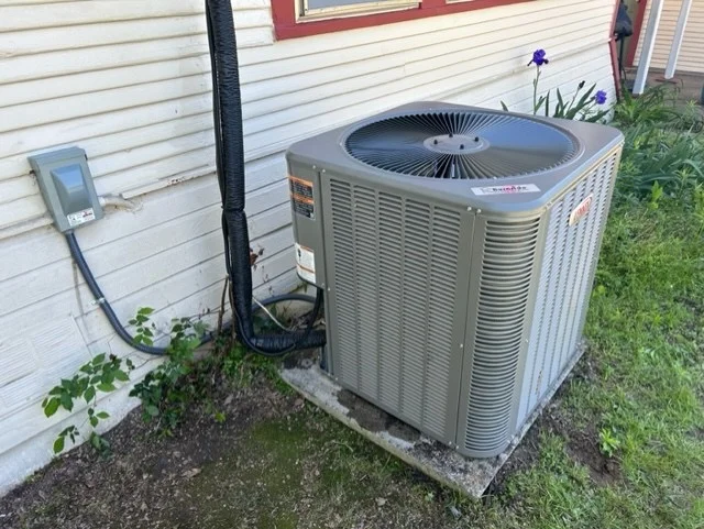 modern outdoor AC unit installed next to a home in a suburban neighborhood