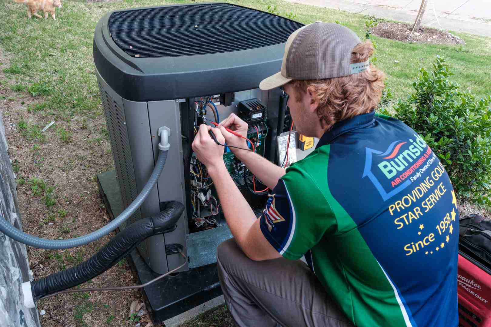 technician testing electrical connections on an outdoor HVAC unit with a digital multimeter technician testing electrical connections on an outdoor HVAC unit with a digital multimeter