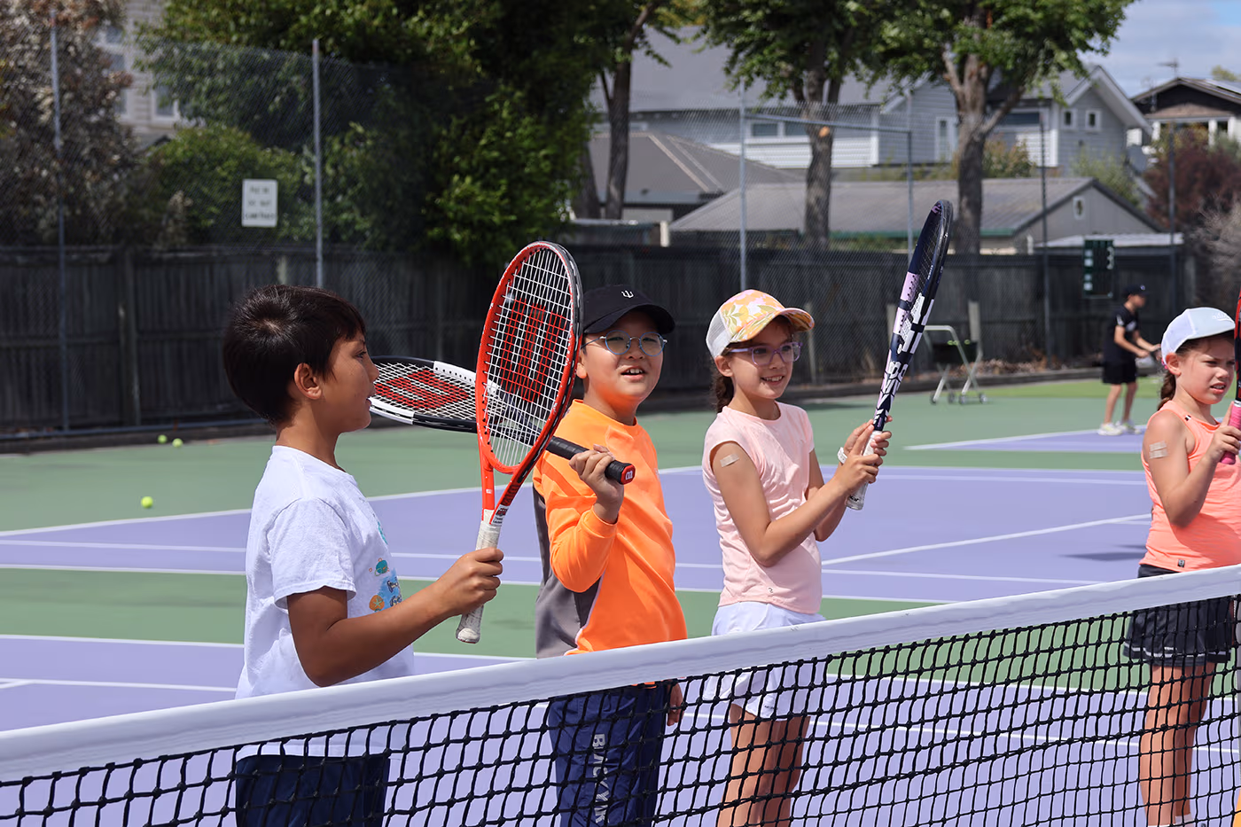 A group of junior tennis players enjoying a coaching session at the Waimairi Tennis Club
