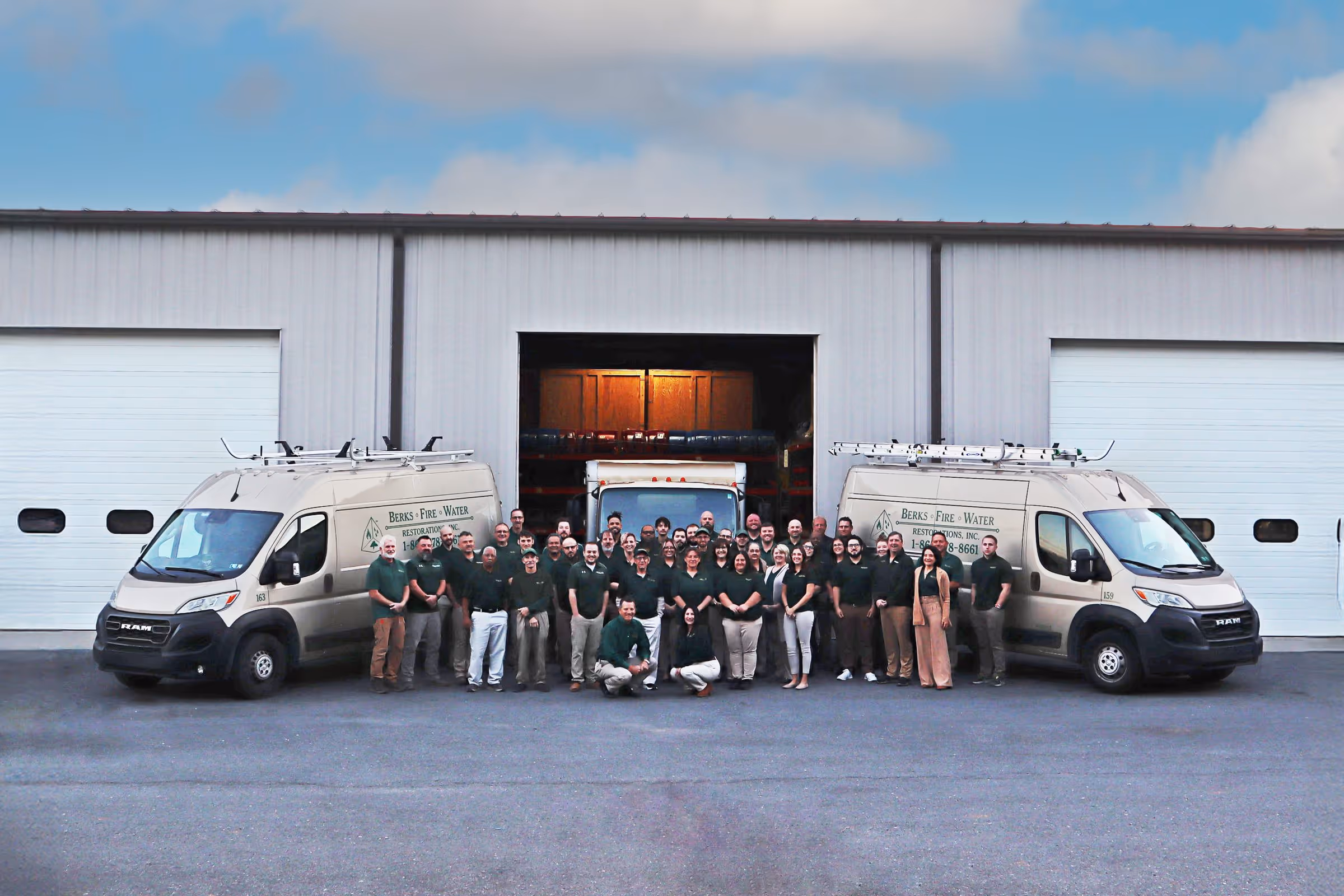 Restoration company crew photographed outside their facility under a clear sky.