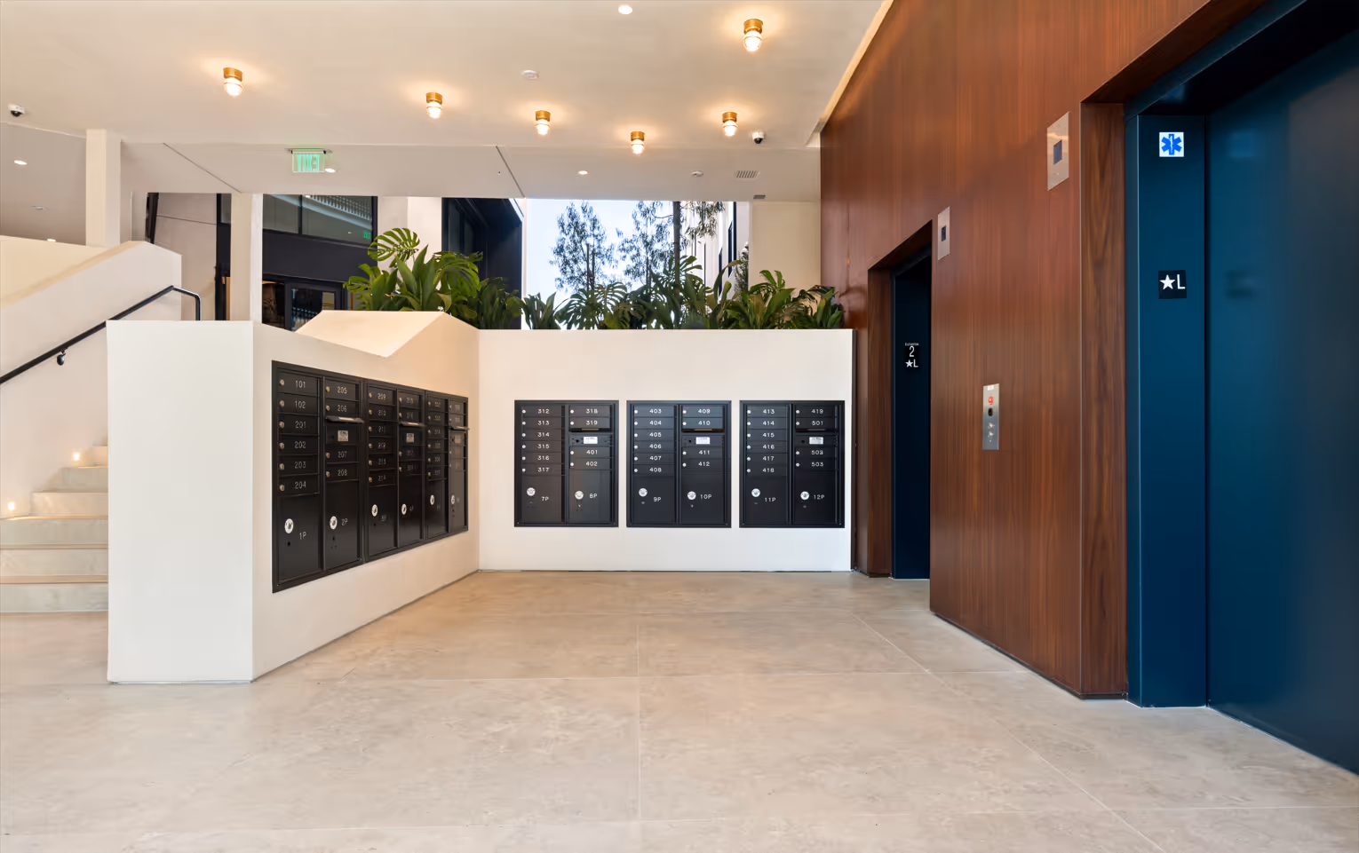 Well lit lobby with mailboxes, elevators and staircase