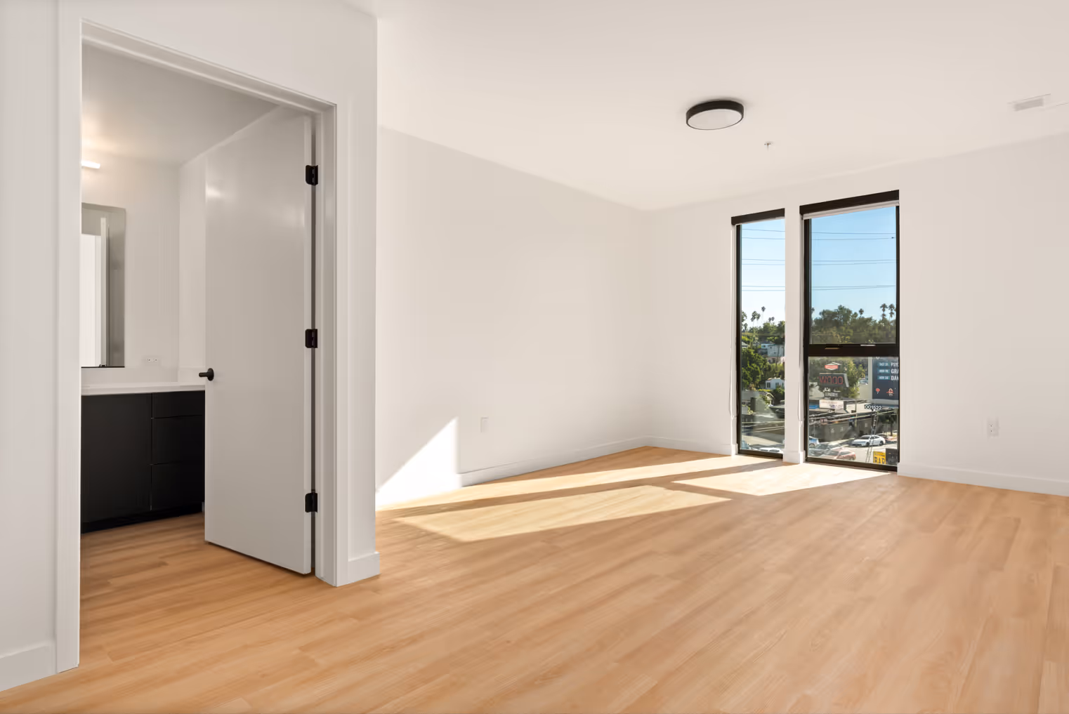 Interior apartment living area showing entrance to bathroom and large windows