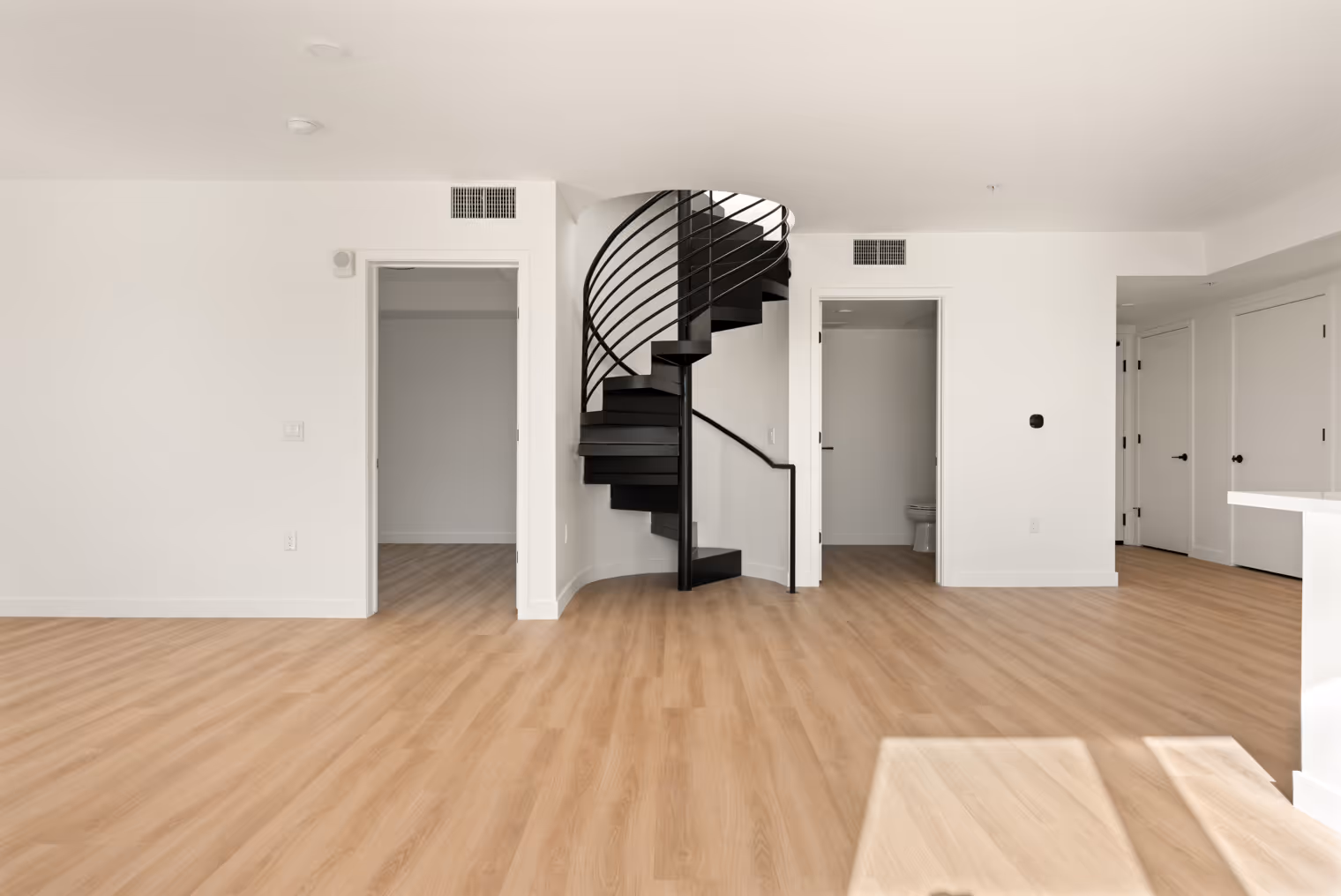 Interior apartment living area facing two rooms and a staircase