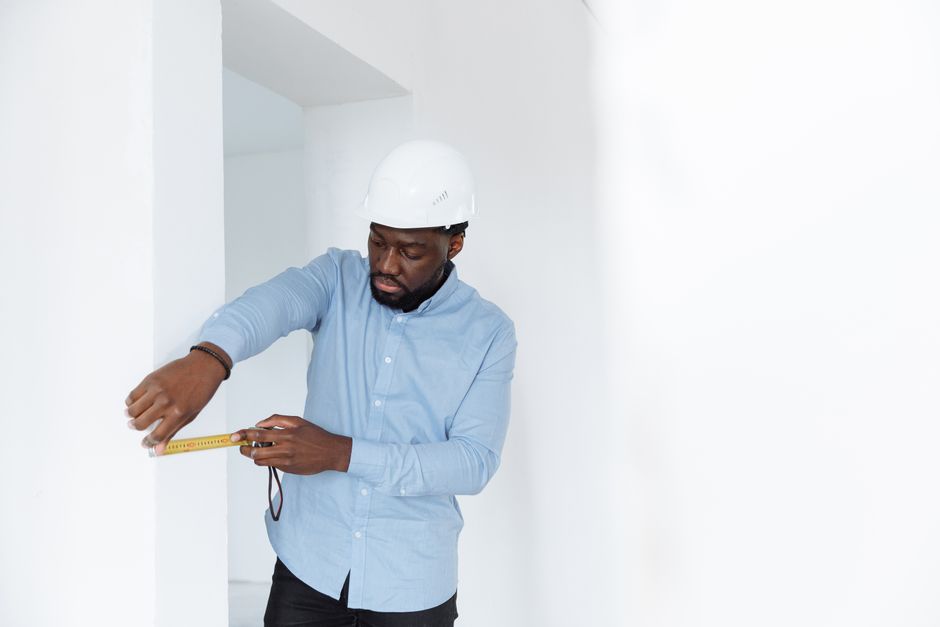 Contractor measuring the inside of an old wood window frame with a tape measure Contractor measuring the inside of an old wood window frame with a tape measure