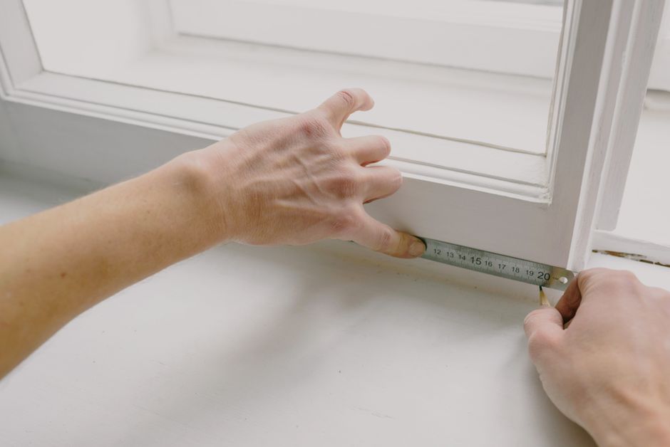 contractor measuring a window frame - cost of putting in new windows