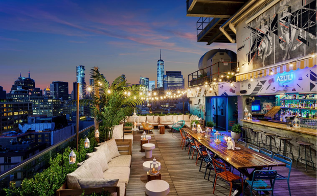 Rooftop bar, city skyline, string lights, communal table at Spring NY in Tribeca