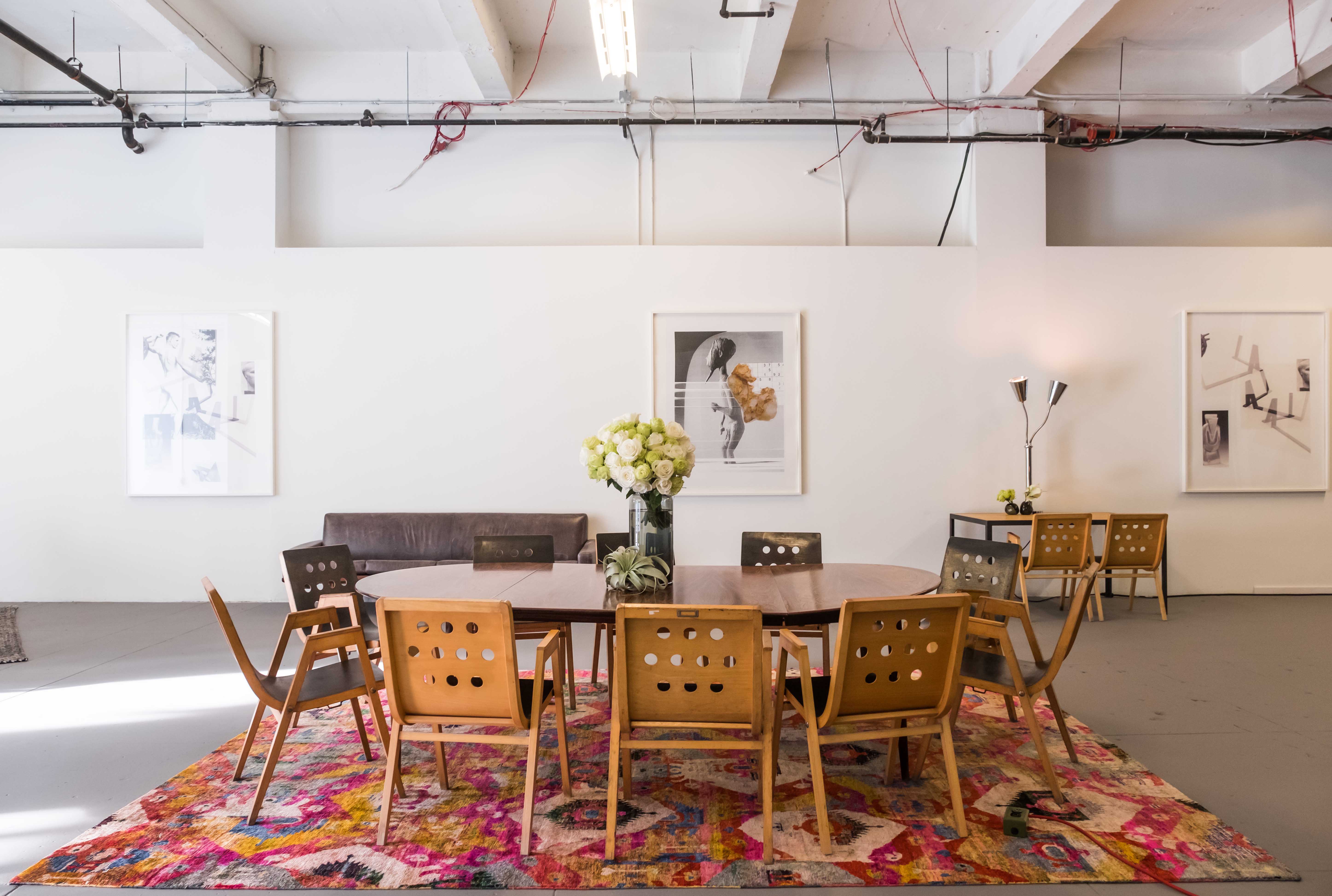Bright, modern decorated area with round wooden table, mid-century chairs, and colorful patterned rug.
